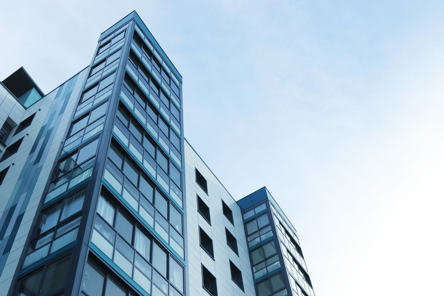 Low-shot view of an apartment building against blue city sky.